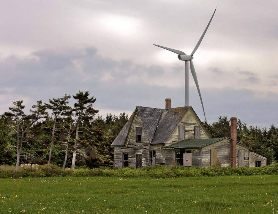An old abandoned  house in Prince Edward Island contrasts with the modern wind turbine.