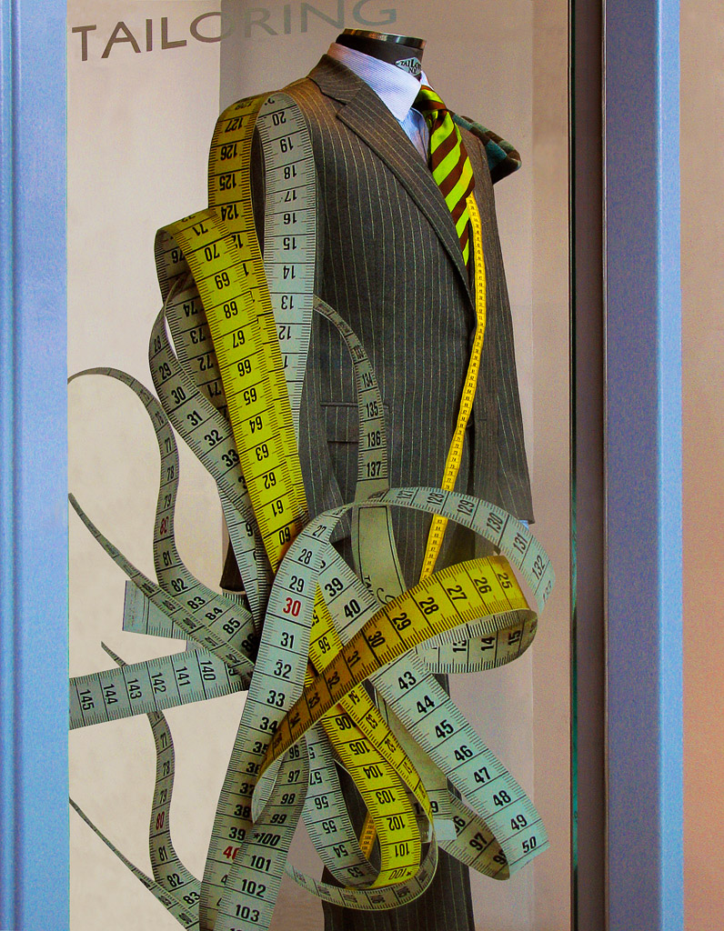 A tailor shop display made interesting with  the use of a tape measure.