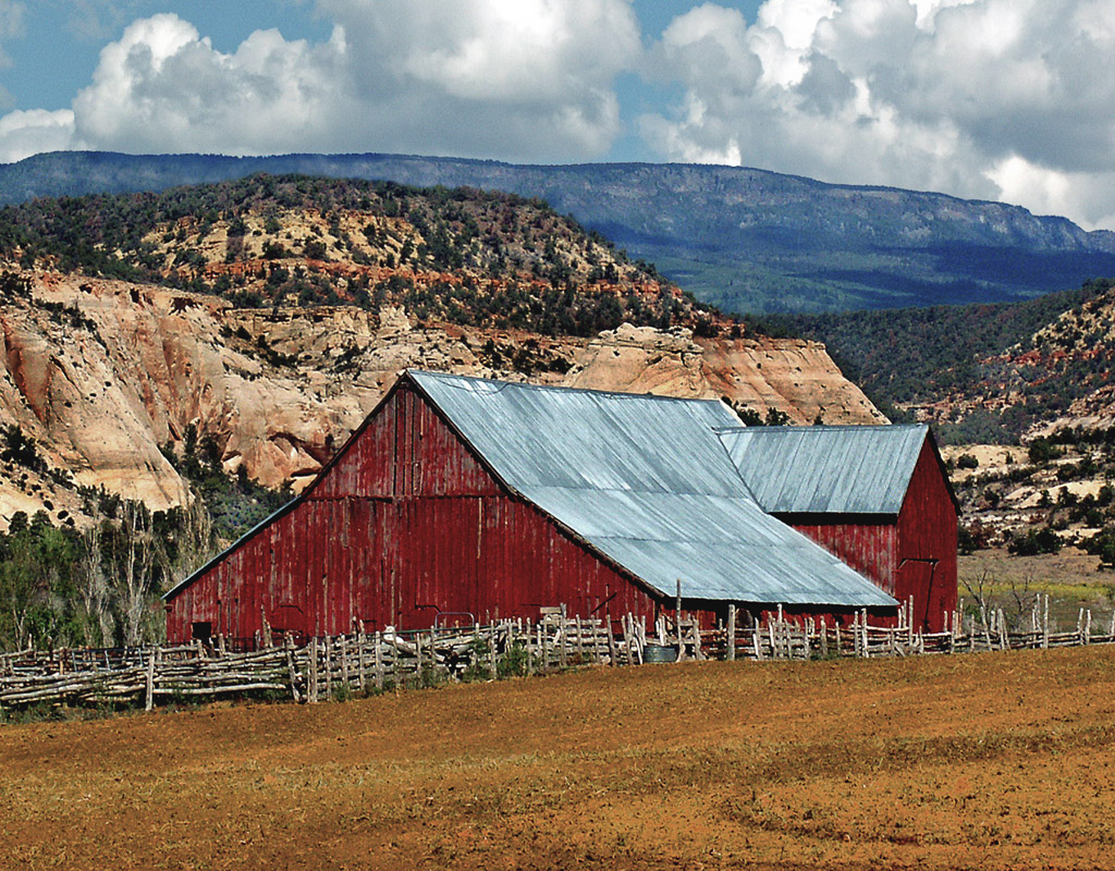 An old barn set among  older rocks, golden fields and a big western sky.
